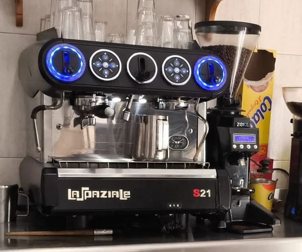 La cafetera de la barra, con el molinillo al lado.